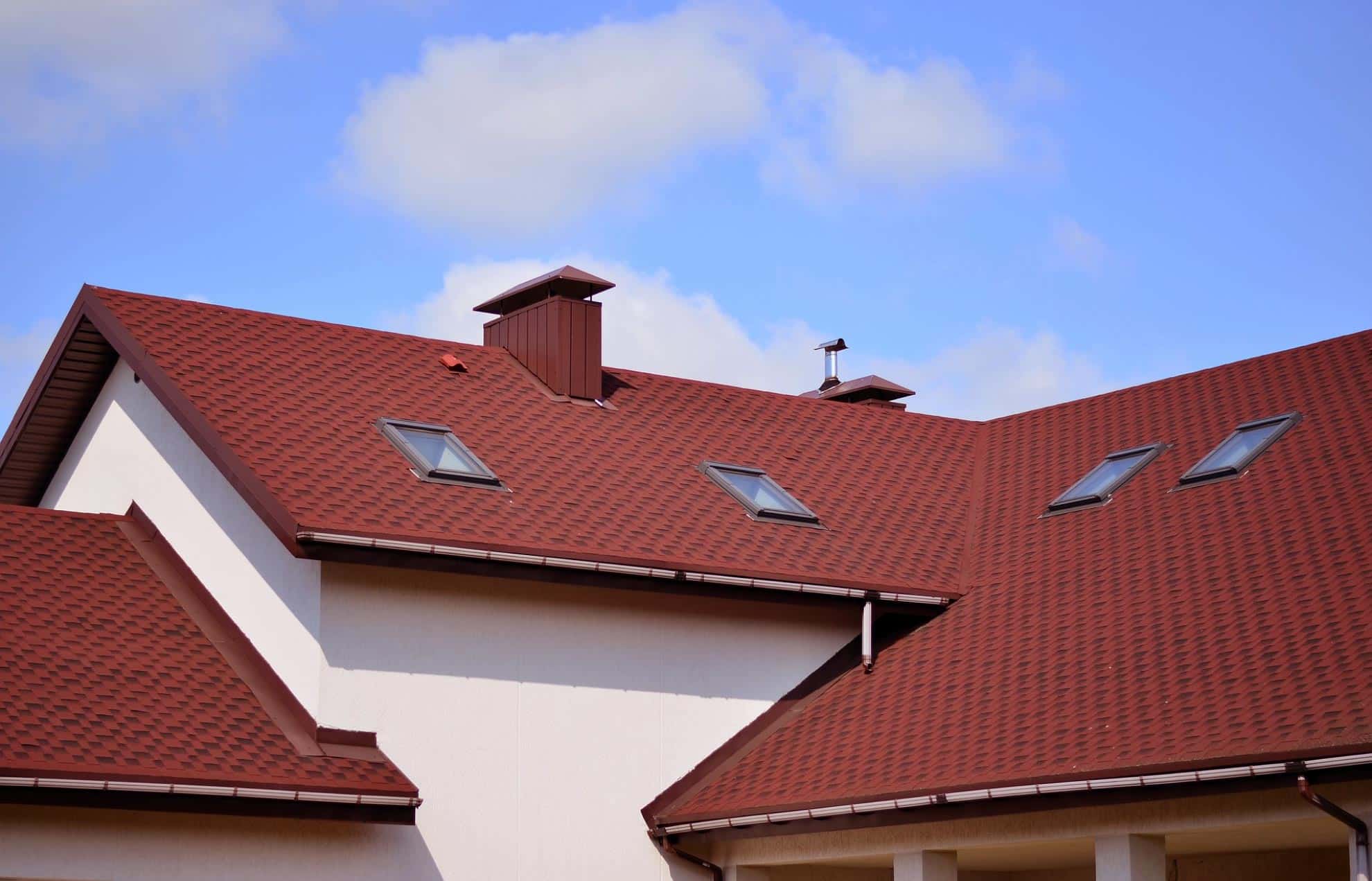 Red shingle roof on a house with chimney and skylights