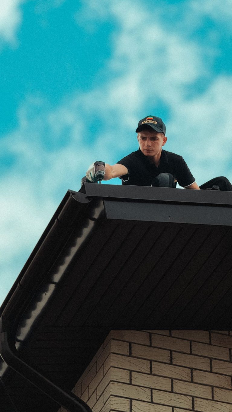 Installer working on a dark eavestrough at a roof edge
