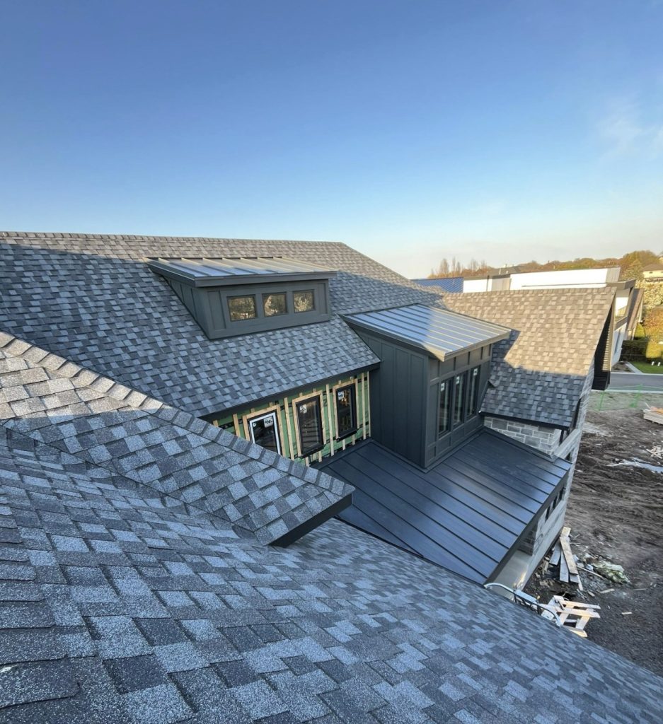New grey shingle roof with metal-accent dormers on a custom home