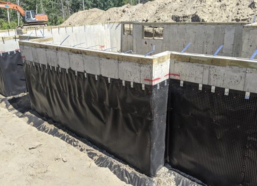 Foundation walls covered in drainage membrane with gravel drainage bed