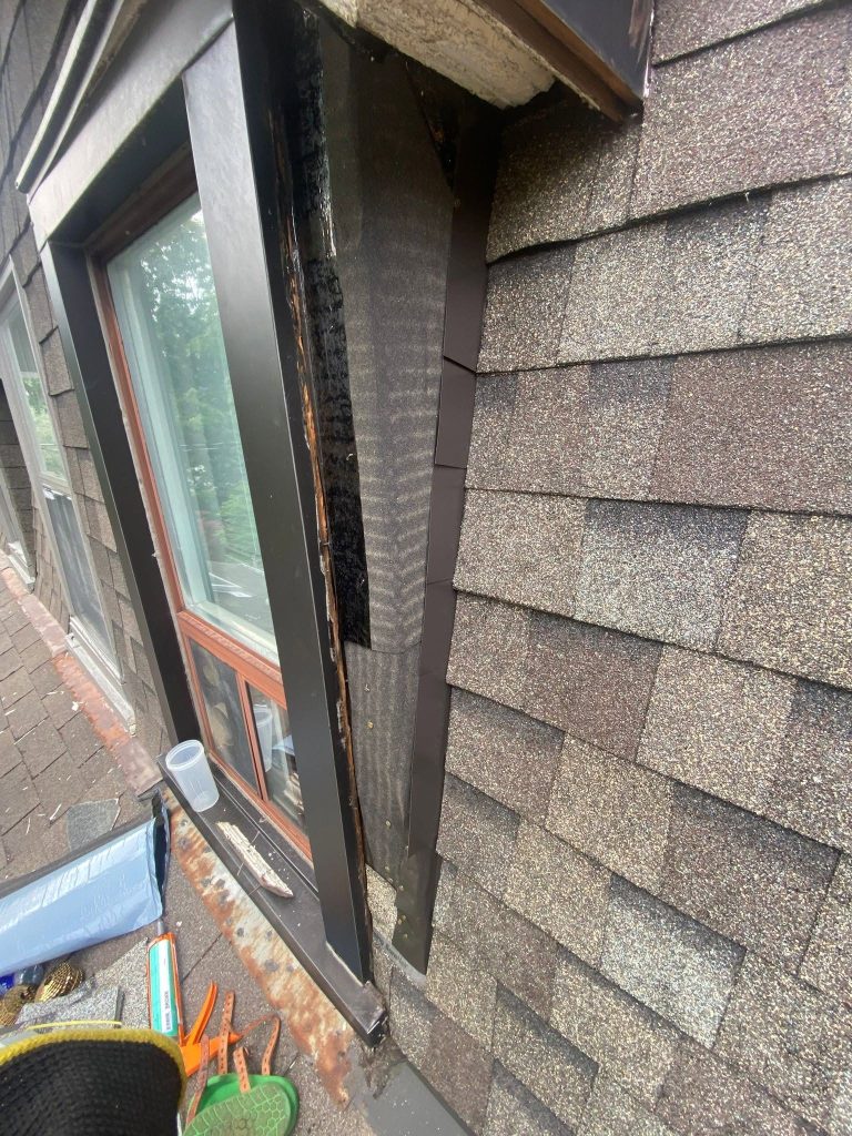Dormer window flashing repair with new underlayment on a brown shingle roof