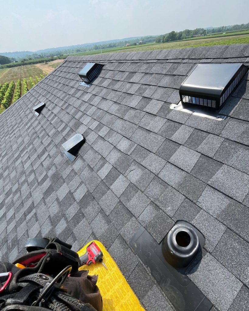 New grey shingle roof with roof vents and a plumbing pipe boot installed