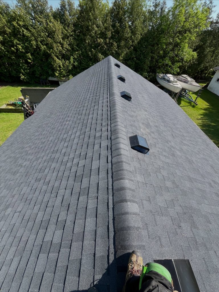 New grey shingle roof ridge with ridge vents and box vents