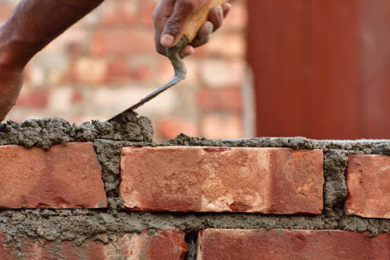 Mason laying brick with mortar and a trowel