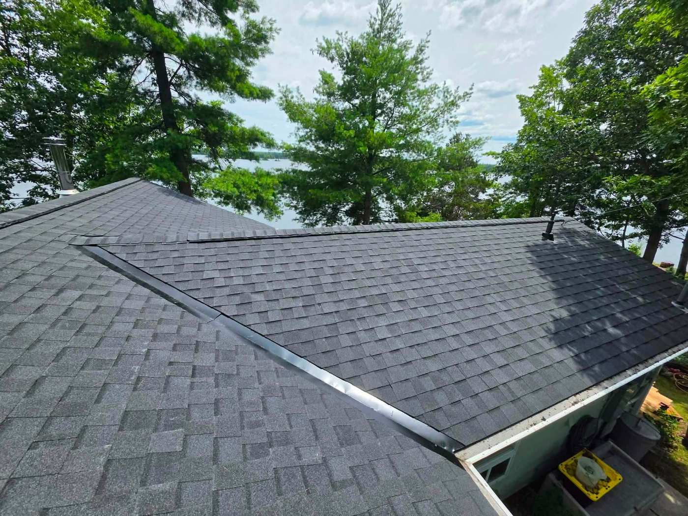 Dark shingle roof with chimney pipe by the lake